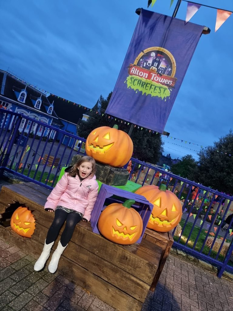 Child sitting among Halloween pumpkins at Alton Towers Scarefest.